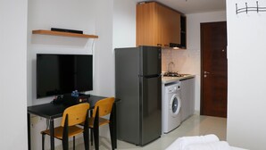 Una cocina compacta con refrigerador, lavadora y comedor con sillas y mesa.