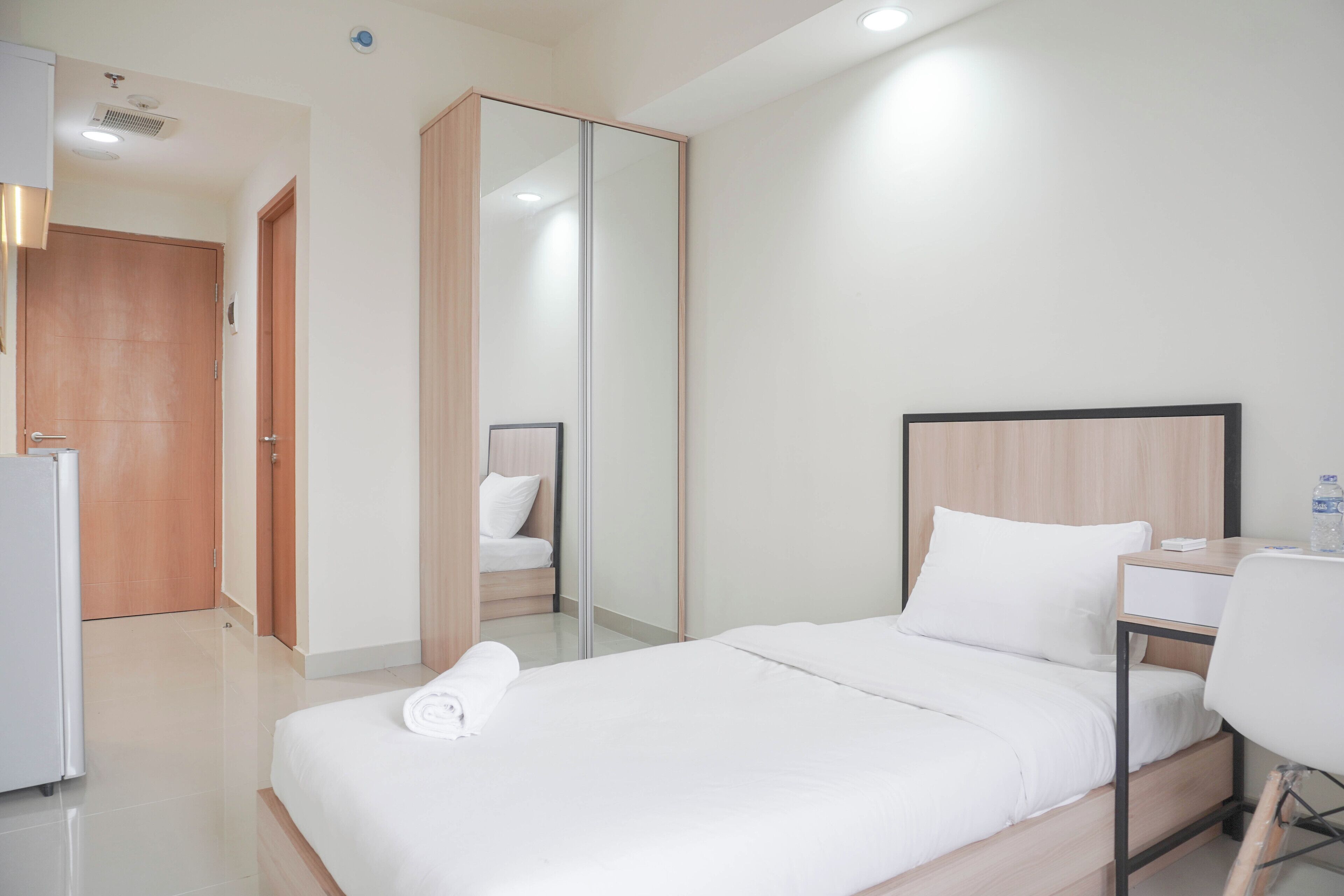 Una camera d'albergo con un letto, una scrivania, una sedia, un armadio e uno specchio.
