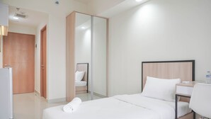 Una camera d'albergo con un letto, una scrivania, una sedia, un armadio e uno specchio.
