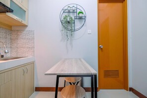 Una cocina con una mesa de madera, una estantería para plantas en la pared y una puerta.