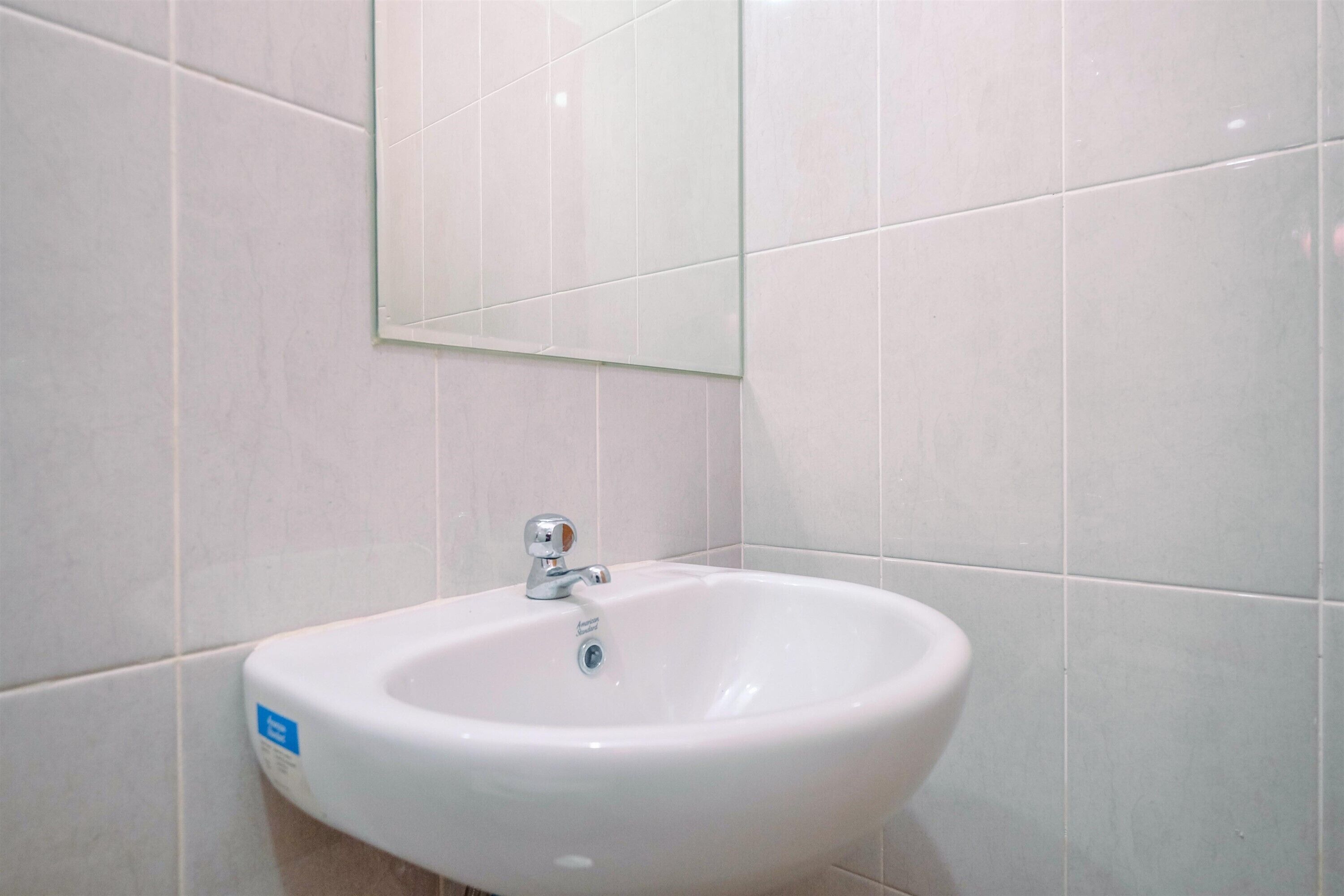 A bathroom with a white sink, a mirror, and white tiled walls.
