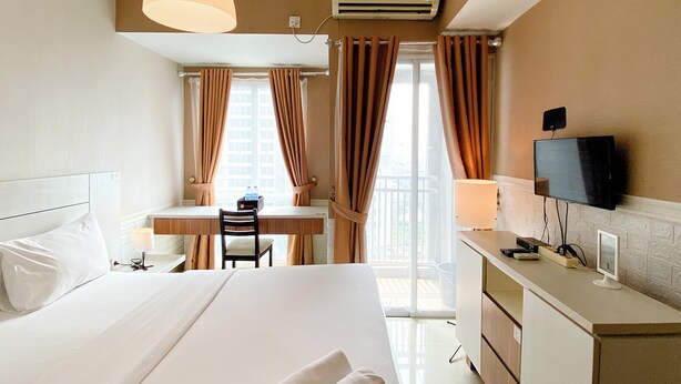 Una camera d'albergo con un letto, una scrivania, una sedia, una televisione e un condizionatore d'aria.