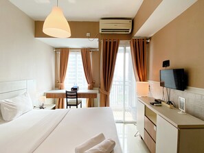 Una camera d'albergo con un letto, una scrivania, una sedia, una televisione e un condizionatore d'aria.