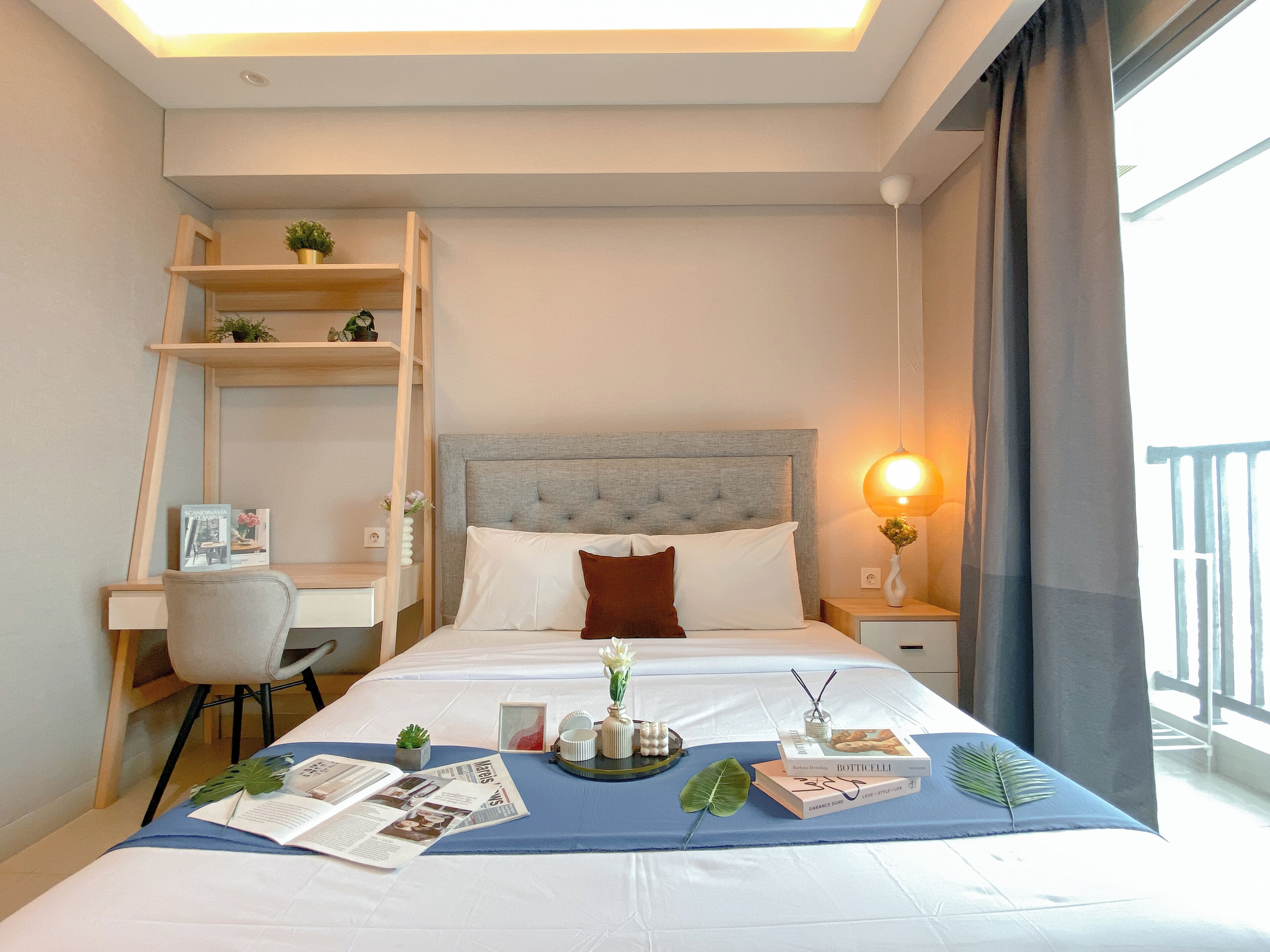 A hotel room with a bed, a desk, a chair, and a window with curtains.