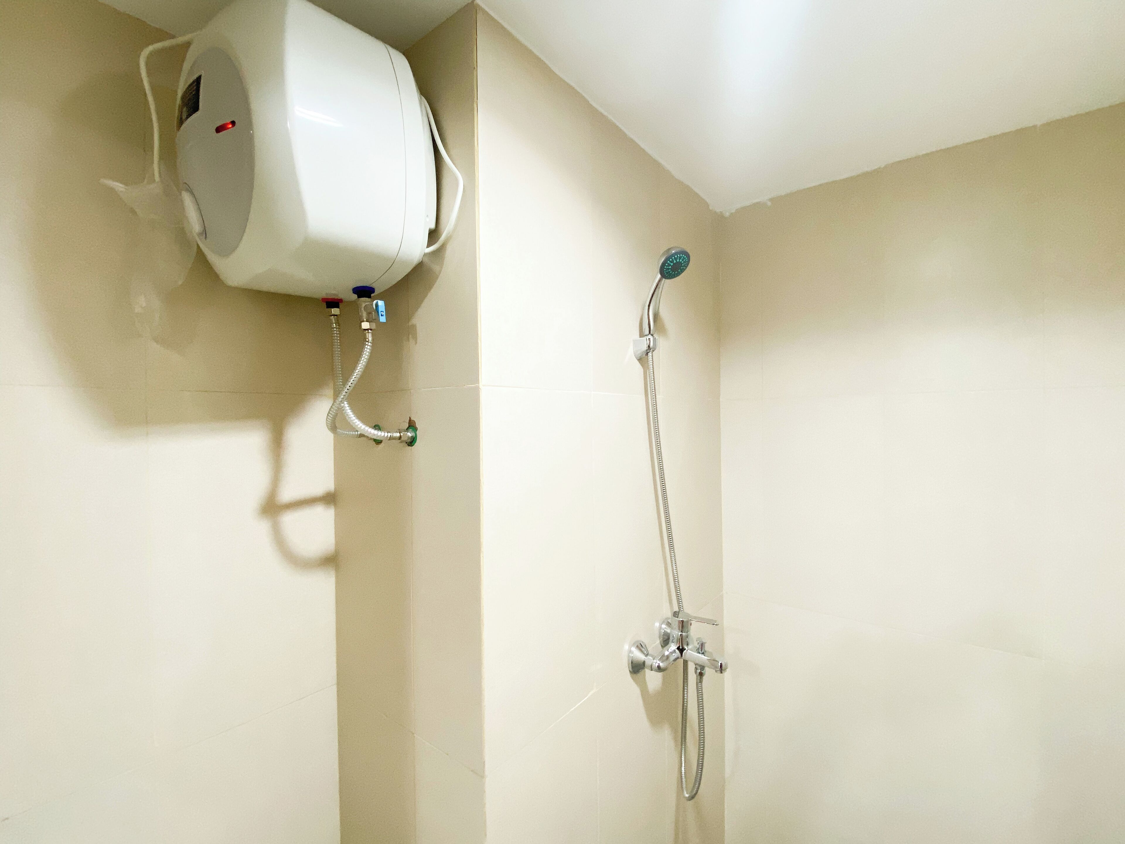 A bathroom with a white showerhead, a handheld shower, and a wall-mounted air conditioning unit.