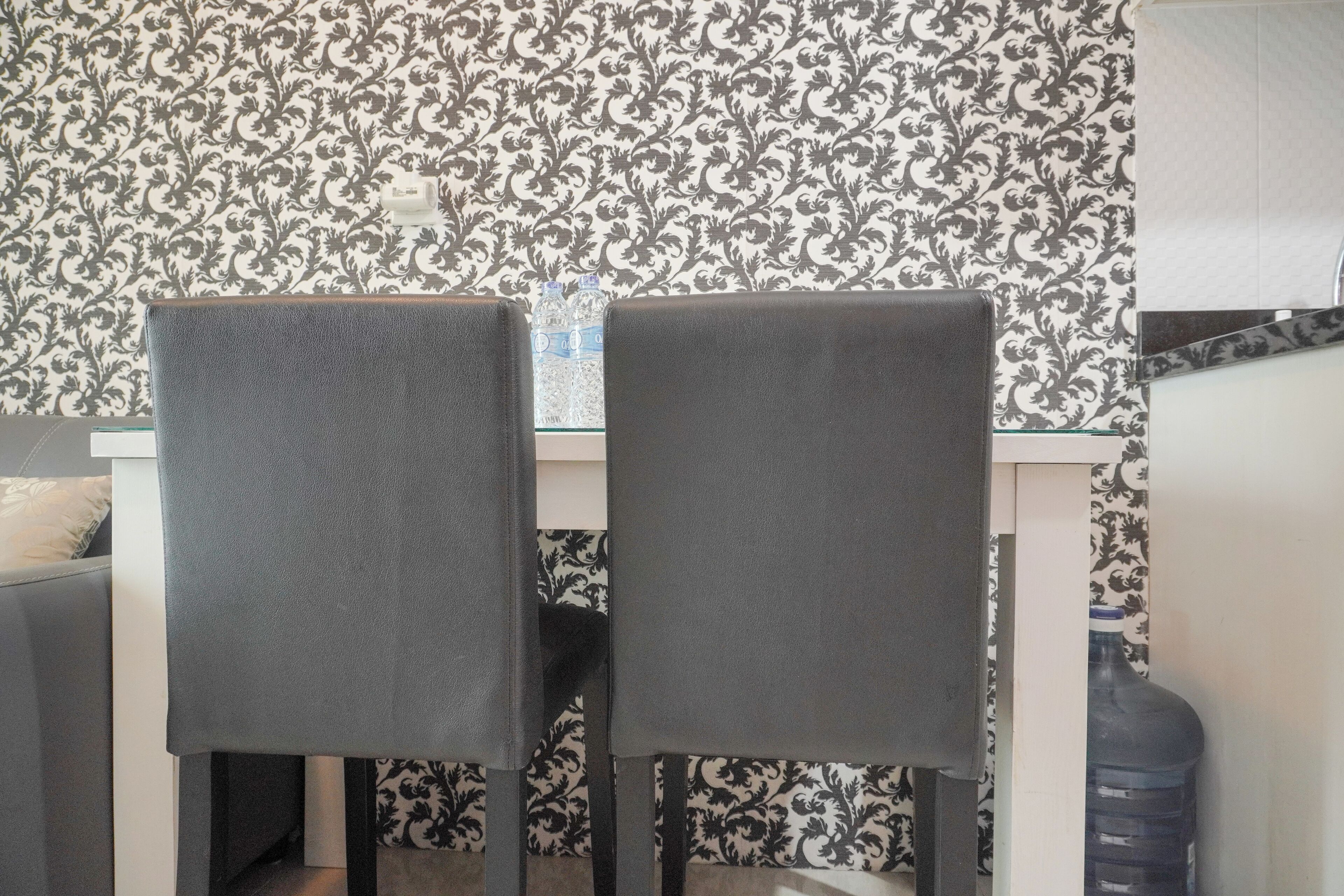 A dining area with two grey chairs, a table, and a water dispenser.