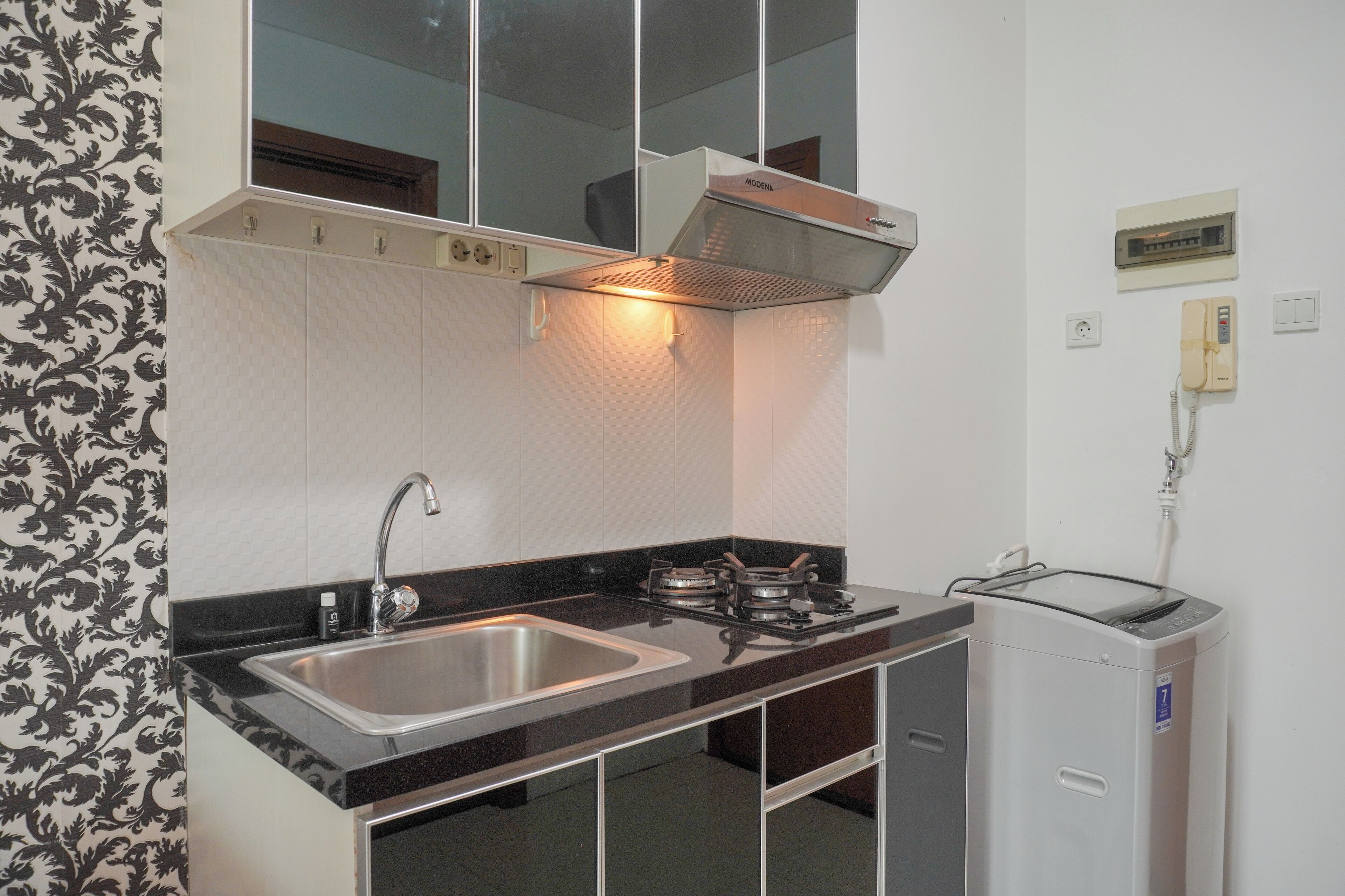 A kitchen with a sink, stove, and a small refrigerator.