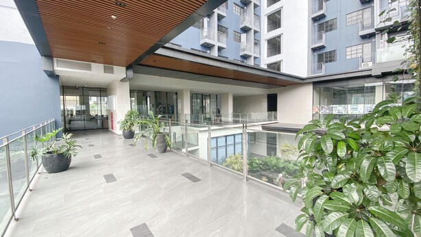A modern building with a glass balcony, potted plants, and a wooden ceiling. - Cozy Studio At 32Th Floor Evenciio Margonda Apartment (Depok)