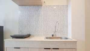 A kitchen with a tiled backsplash, a stainless steel sink, and a built-in scale on the countertop. - Cozy Studio At 32Th Floor Evenciio Margonda Apartment (Depok)