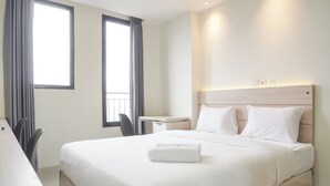 A hotel room with a large bed, a desk, and a chair. - Cozy Studio At 32Th Floor Evenciio Margonda Apartment (Depok)