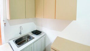 A compact kitchen with a sink, a small countertop, and beige cabinets. - Well Furnished And Cozy Studio Paltrow City Apartment (Semarang)