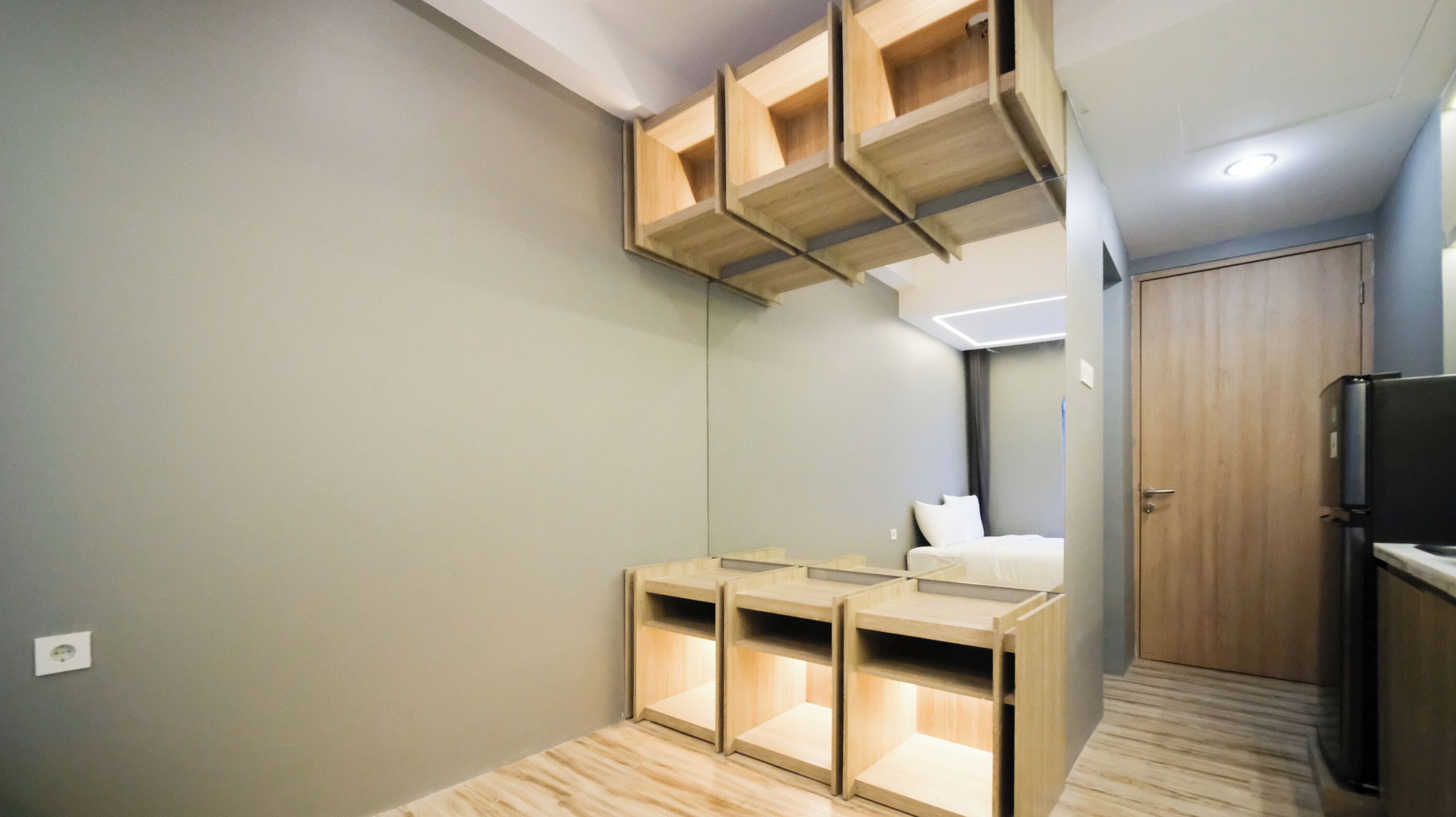 Habitació d'hotel petita amb armari integrat, una petita taula de nit i un mirall.