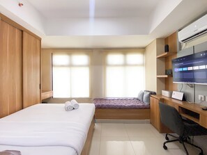 Une chambre d’hôtel avec un lit, un bureau, une chaise, une télévision et une fenêtre.