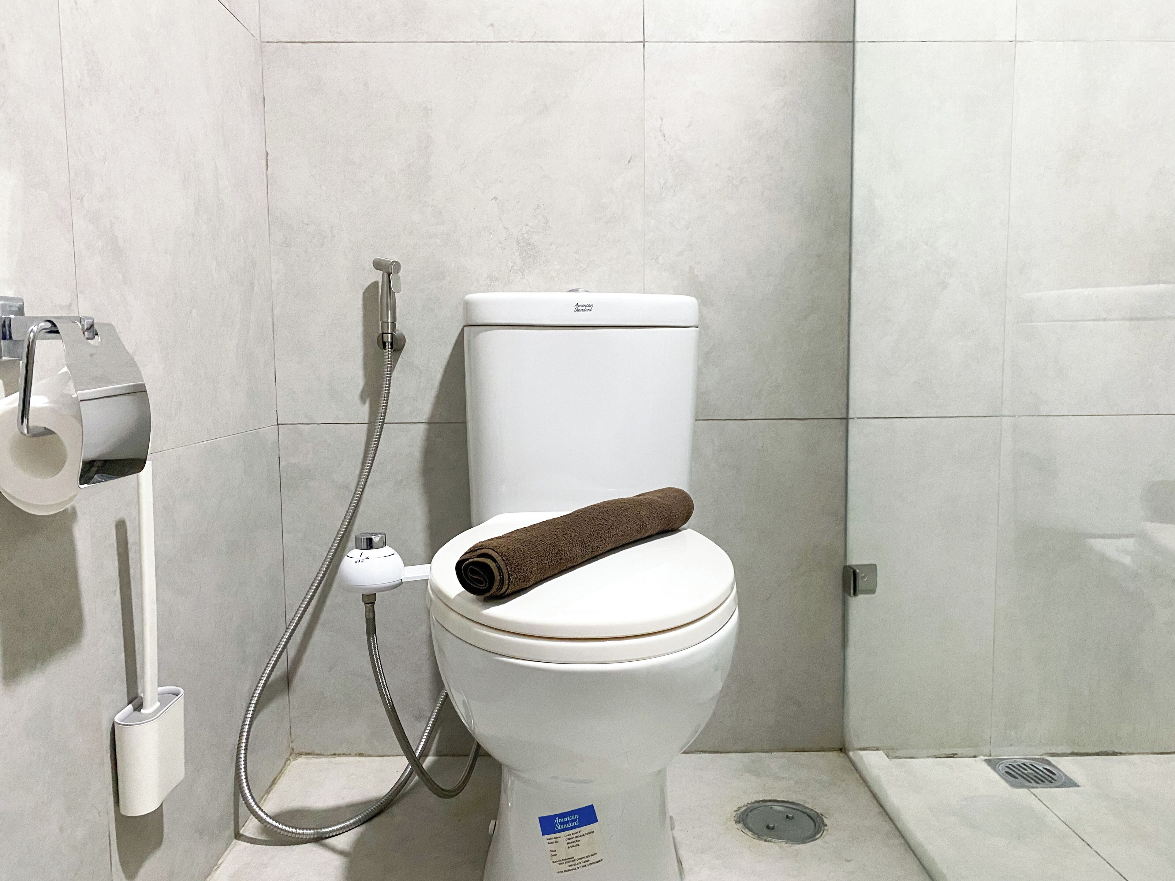Ein modernes Badezimmer mit Toilette, Dusche und Toilettenpapierhalter.