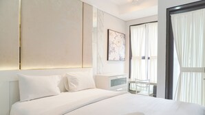 A modern hotel room with a large bed, a bedside table, a chair, and a window with curtains. - Modern Look And Nice Studio Transpark Bintaro Apartment (South Tangerang)