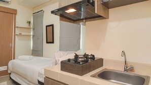 A modern kitchen with a built-in stove, a stainless steel sink, and wooden cabinetry. - Good Deal And Restful Studio Apartment B Residence (Pagedangan)