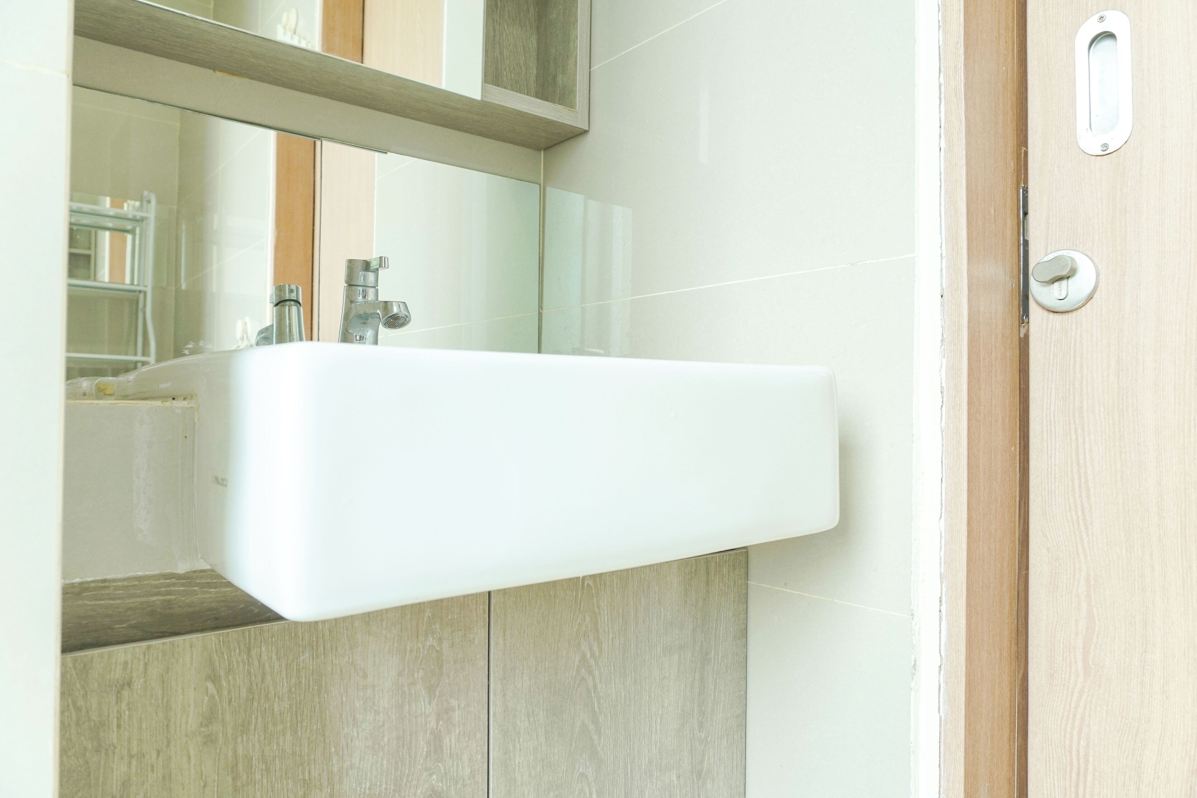 A bathroom with a white sink, a mirror, and a wooden door.