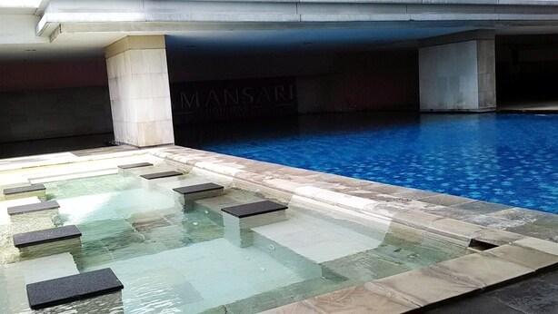 A swimming pool with clear water, stone steps leading into the pool, and a sign reading "MANSARI." - Good Deal And Restful Studio Tamansari Sudirman Apartment (Jakarta)