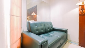 A room with a green leather sofa, a mirror, a lamp, and a wooden door. - Good Deal And Restful Studio Tamansari Sudirman Apartment (Jakarta)