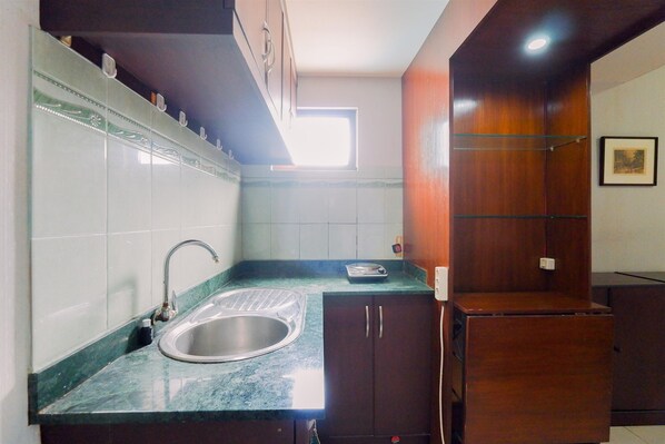 Una cocina compacta con un lavabo, armarios y una ventana.