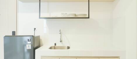 A kitchen with a stainless steel refrigerator, a sink, and wooden cabinets.