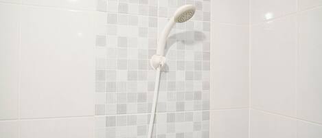 Ducha con cabezal curvo y grifo blanco sobre un muro con azulejos.