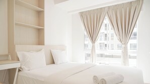 Een hotelkamer met een bed, een bureau en een raam met gordijnen.