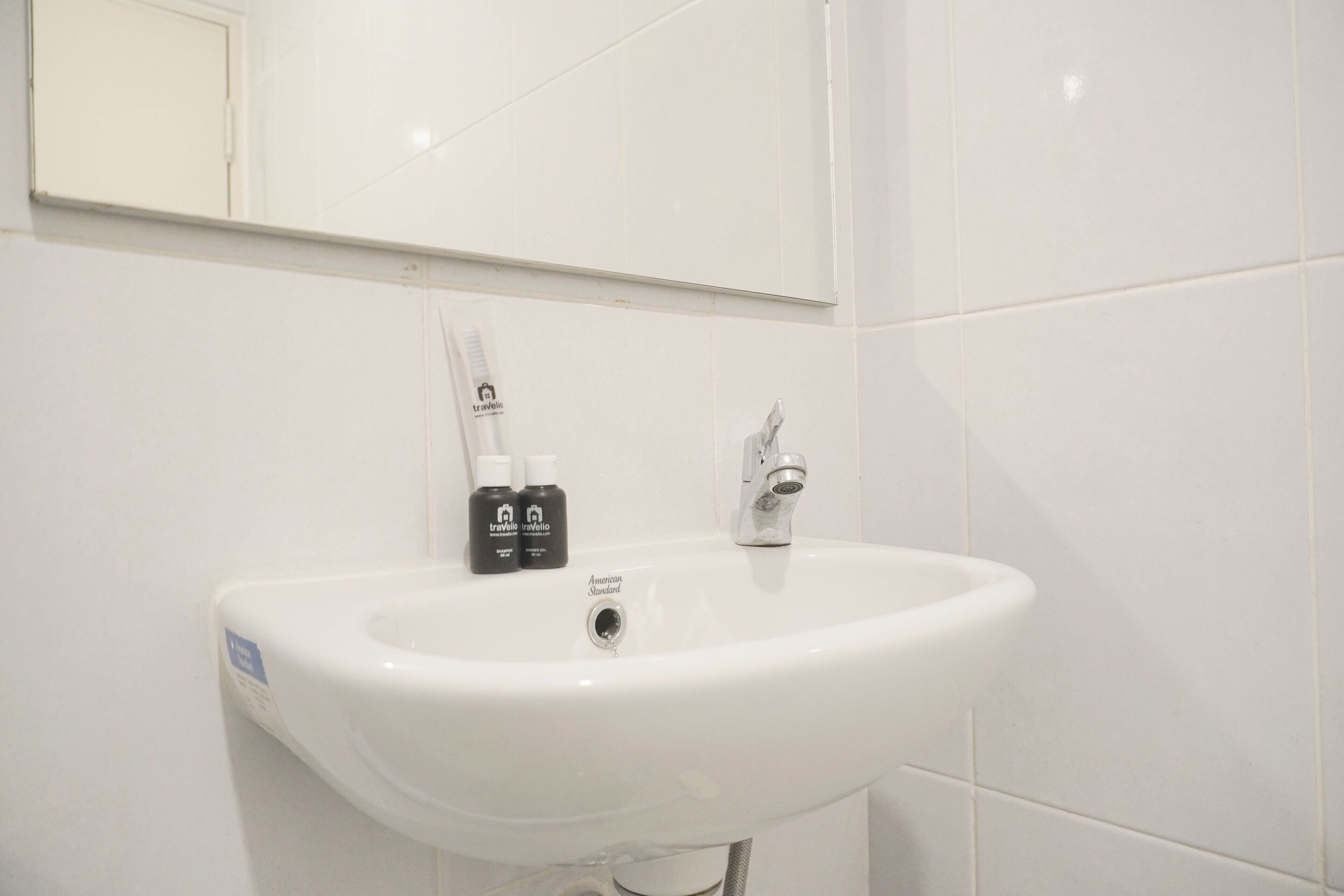A white bathroom sink with a mirror above it and two bottles of toiletries on the sink.