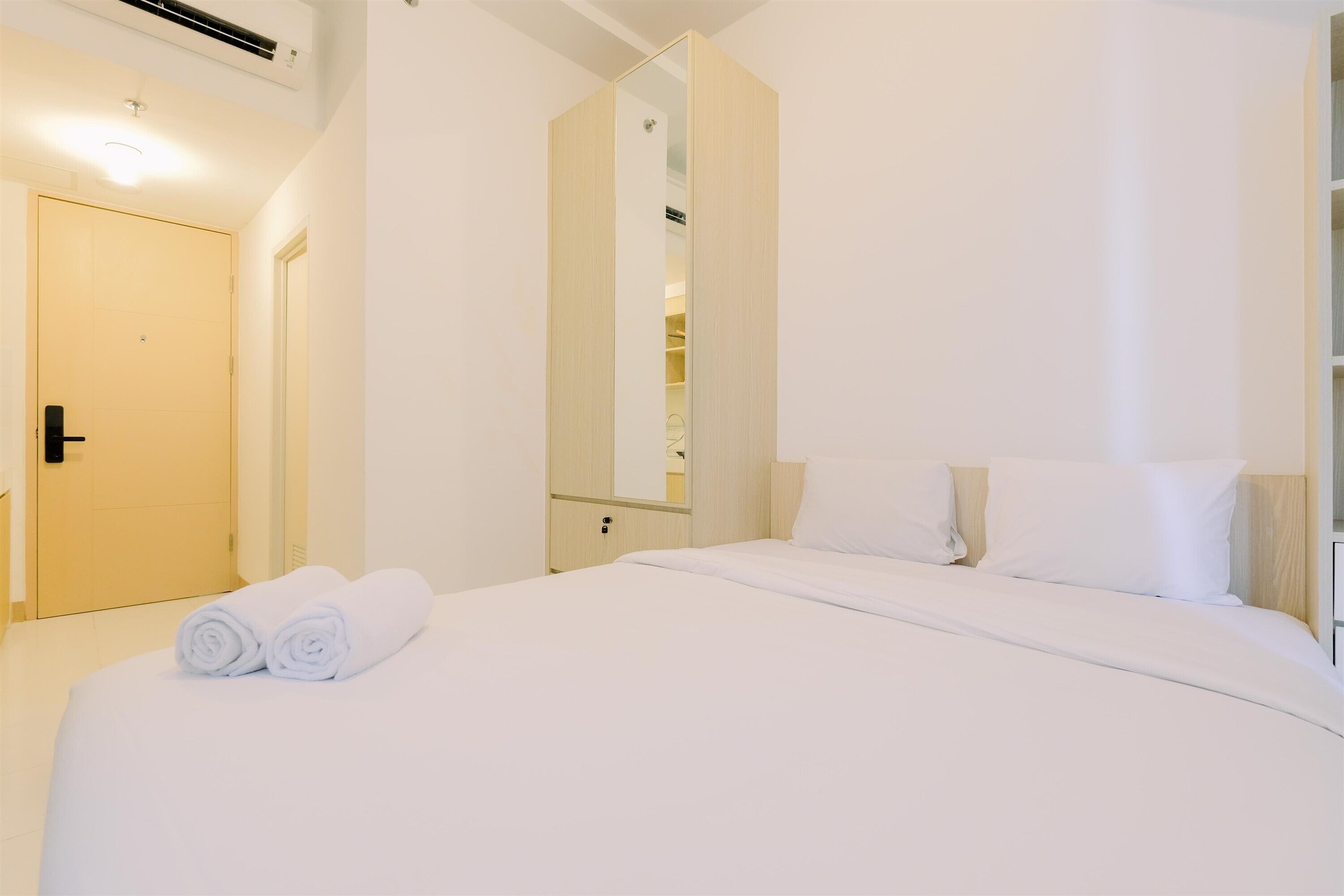 A hotel room with a bed, a wardrobe, a mirror, and a door.
