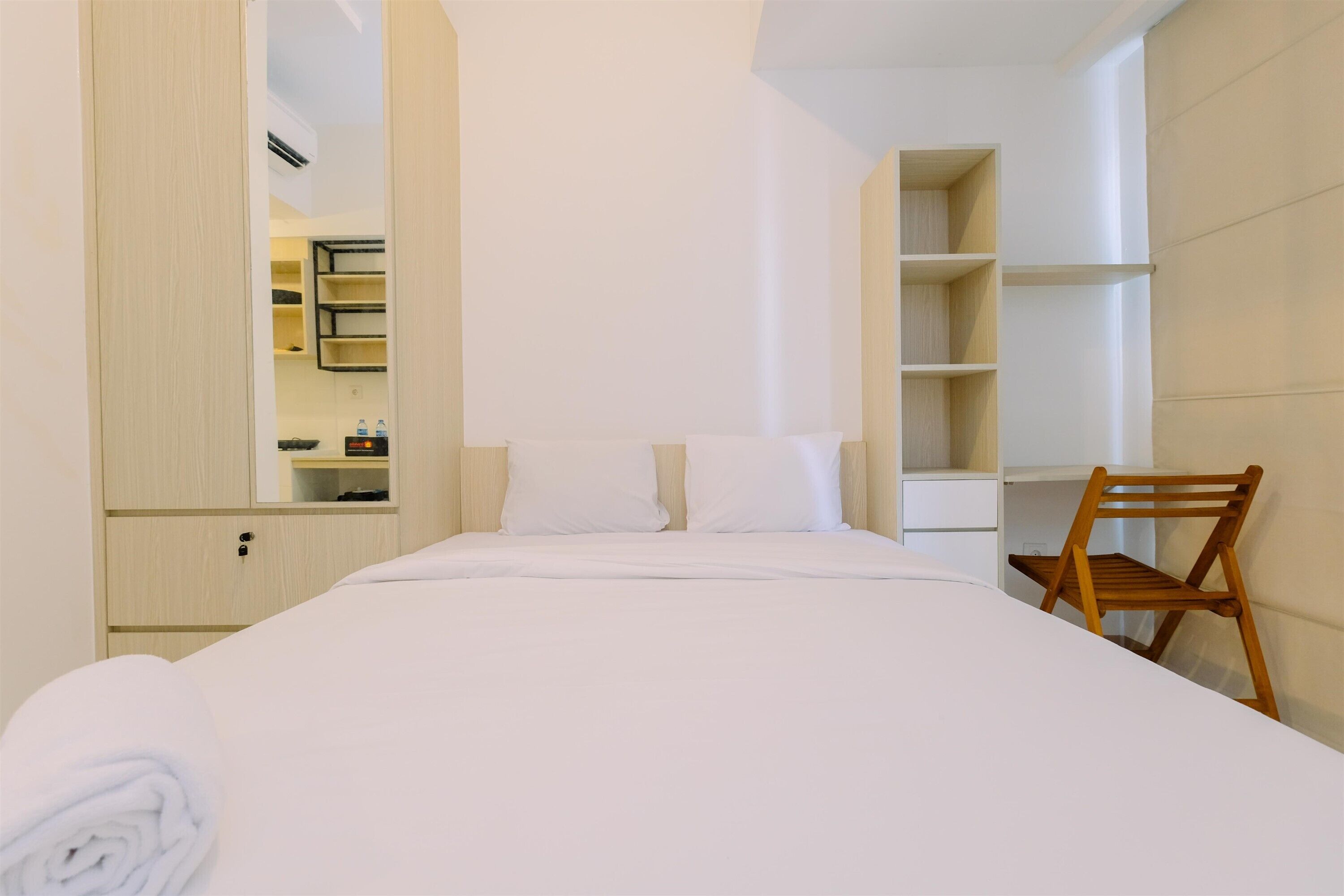 Una camera d'albergo con un letto, una sedia di legno, una scrivania e uno specchio.