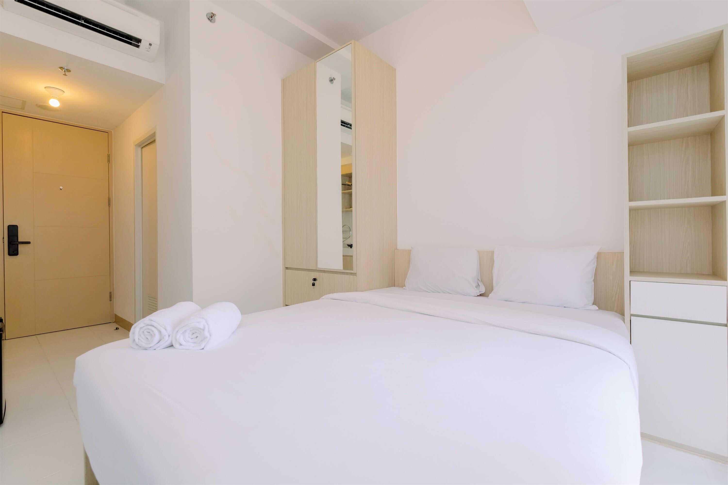 A hotel room with a large bed, a wardrobe, a mirror, and a door.