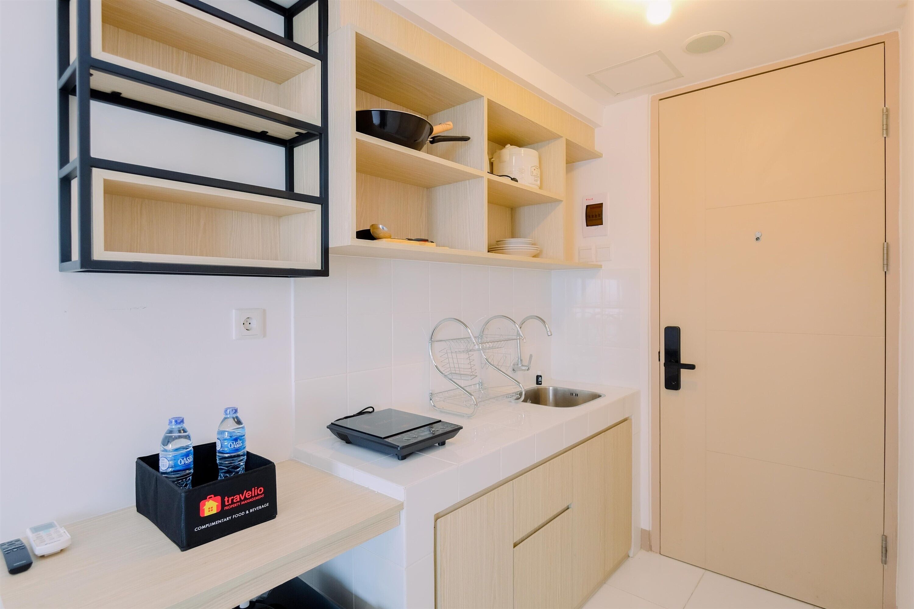A compact kitchen with a sink, shelves, and a door.