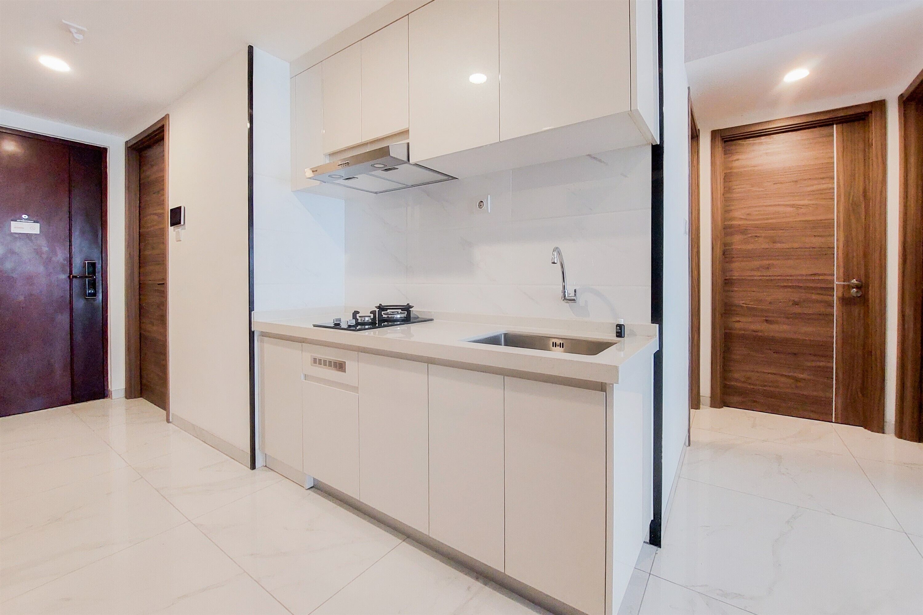 A modern kitchen with white cabinetry, a stainless steel sink, and a built-in oven.