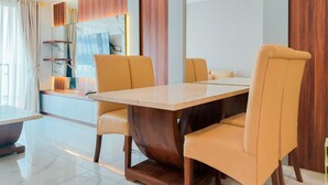 A modern dining area with a marble-top table, cushioned chairs, and a wooden base.