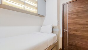 A single bed with a wooden headboard, a bedside table, and a wardrobe with a wooden finish.
