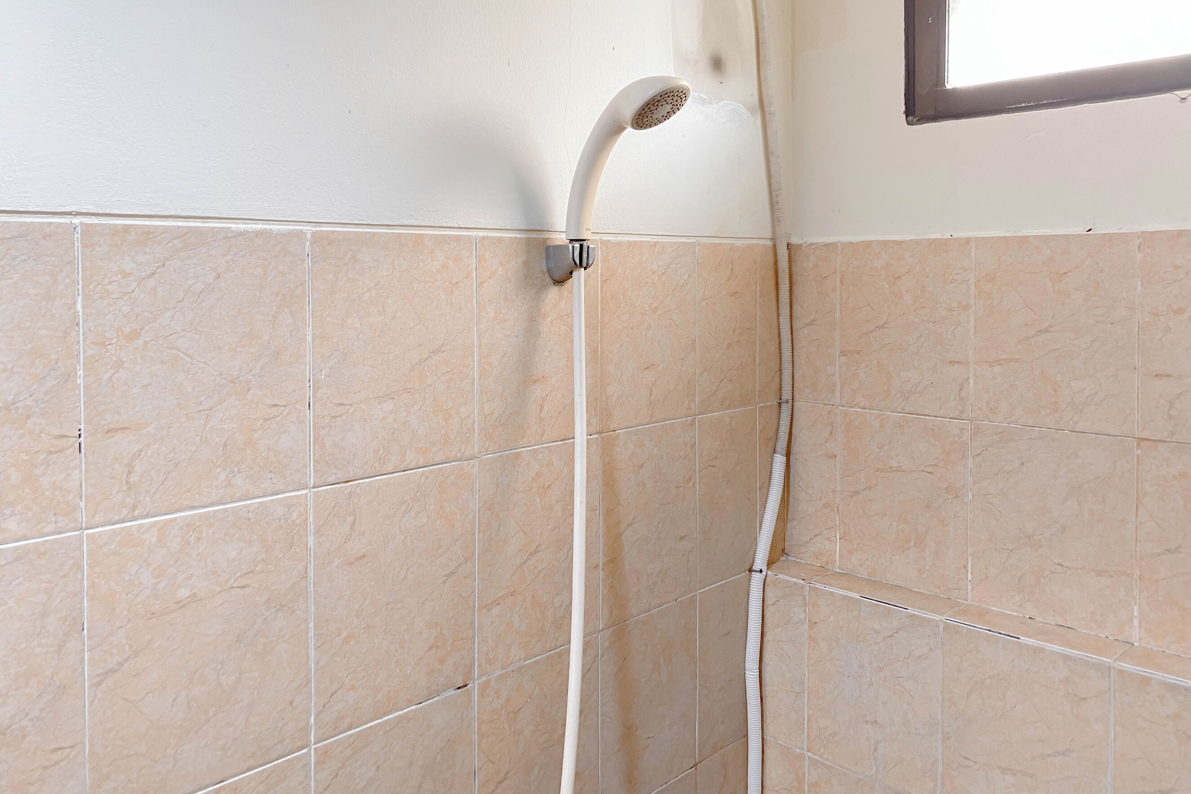 A shower with a curved head and a visible water hose.