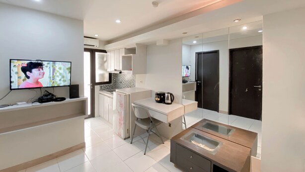 A modern kitchen with a built-in oven, a coffee maker, and a TV mounted on the wall. - Good Deal And Comfy 2Br Kebagusan City Apartment (Jakarta)