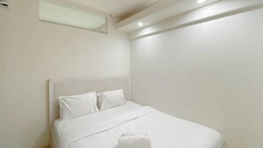 A neatly made bed with white linens and pillows, a folded towel on the bed, and a small window above the bed. - Good Deal And Comfy 2Br Kebagusan City Apartment (Jakarta)