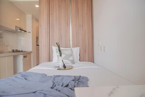 Une chambre moderne avec un lit, une table de chevet et une vue sur la cuisine.