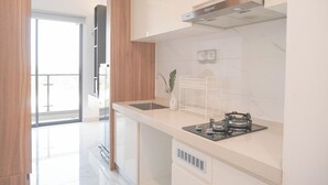 A modern kitchen with a stainless steel range hood, a built-in sink, and a countertop with a gas stove. - Comfortable And Good Place Studio At Sky House Bsd Apartment (Pagedangan)