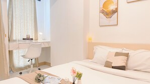 Ein Hotelzimmer mit einem Bett, einem Schreibtisch mit Stuhl, einer Blumenvase und einem gerahmten Bild an der Wand.