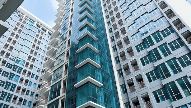 Un edificio moderno de rascacielos con varios pisos, ventanas amplias y balcones.