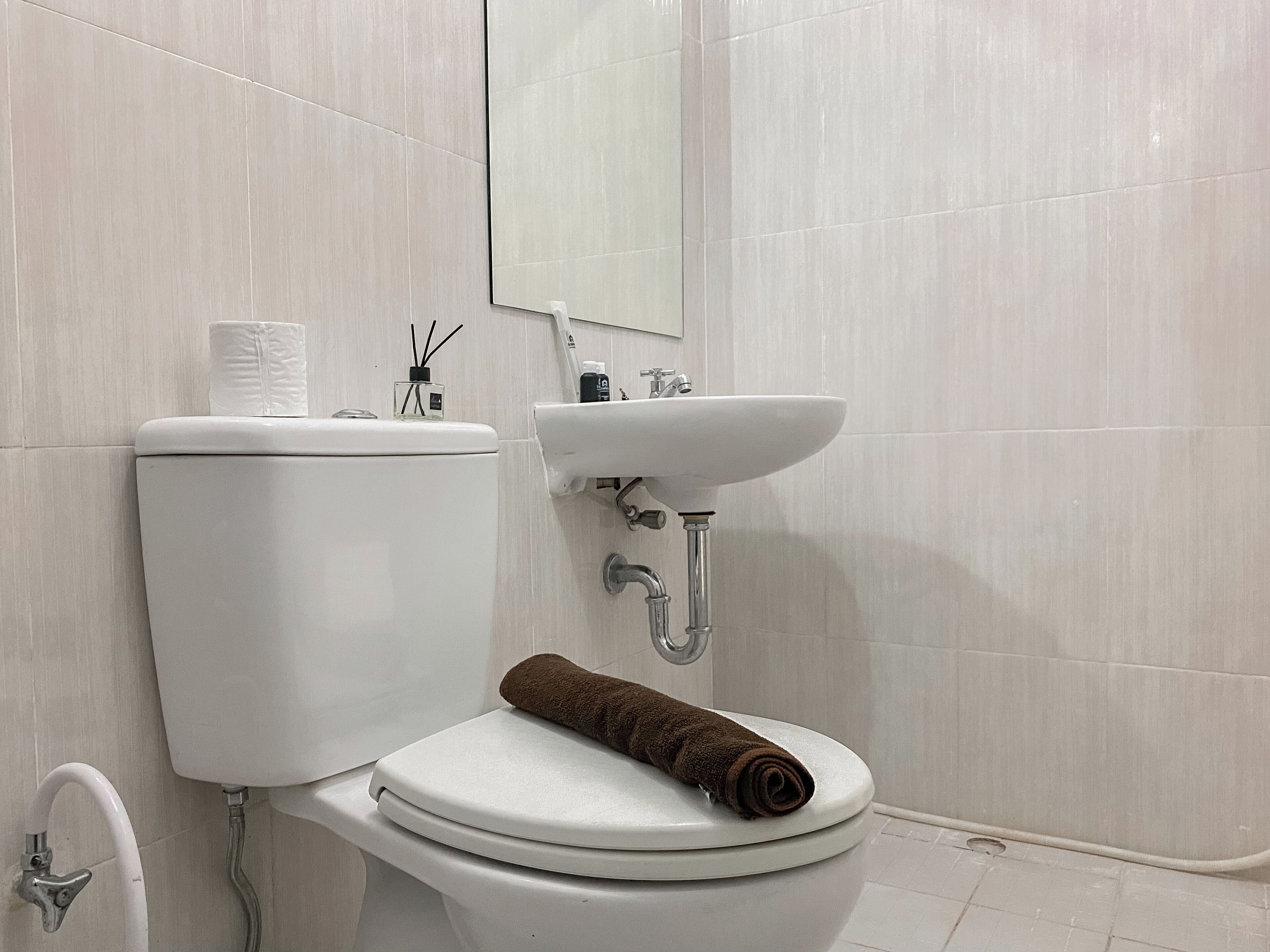 A bathroom with a toilet, sink, and mirror.