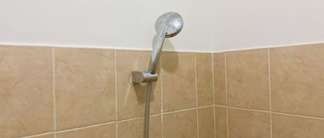 A showerhead mounted on a wall with beige tiles.