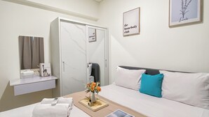 A hotel room with a bed, a bedside table with a vase of flowers, a framed picture on the wall, and a sign on the door.