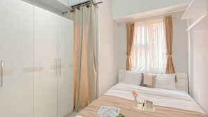 A bedroom with a bed, a wardrobe, and a window with curtains. - Good And Warm Studio Transpark Juanda Bekasi Timur Apartment (Bekasi)
