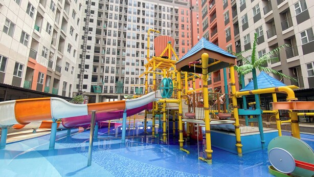 A children's play area with slides and climbing structures, surrounded by high-rise residential buildings. - Good And Warm Studio Transpark Juanda Bekasi Timur Apartment (Bekasi)