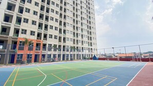 An outdoor basketball court with a multi-colored surface, surrounded by a high-rise building with multiple windows and balconies. - Good And Warm Studio Transpark Juanda Bekasi Timur Apartment (Bekasi)