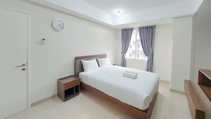 A modern bedroom with a bed, bedside table, and a clock on the wall. - Good Place And Homey 2Br At Podomoro City Deli Medan Apartment (Medan)