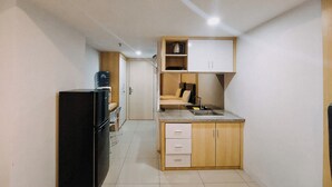 A compact kitchen with a refrigerator, a sink, and wooden cabinets.